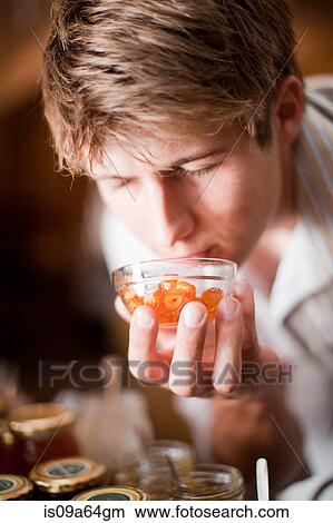 Picture - Man smelling preserves in grocery. Fotosearch