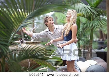 Stock Image - Man splashing girlfriend in fountain. Fotosearch