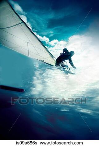 Stock Photograph - Man trimming sails on yacht in race. Fotosearch