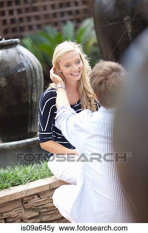 Stock Photo - Man tucking girlfriend's hair behind ear. Fotosearch