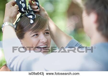Stock Image - Man tying headband on girlfriend. Fotosearch