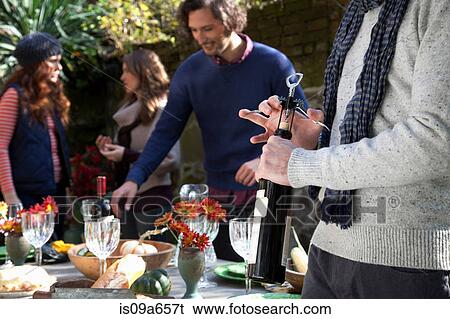 Stock Photograph - Man uncorking bottle of wine at table. Fotosearch