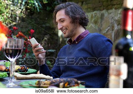 Man using cell phone at table outdoors View Large Photo Image Stock Image - Man using cell phone at table outdoors. Fotosearch