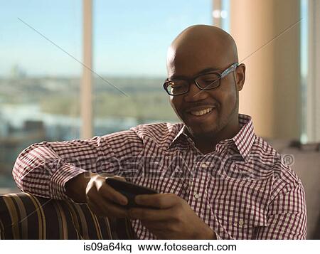 Stock Photography - Man using cell phone on sofa. Fotosearch