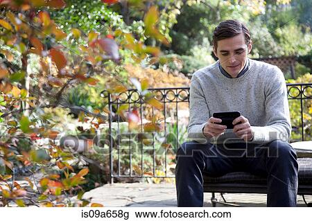Stock Image - Man using cell phone outdoors. Fotosearch