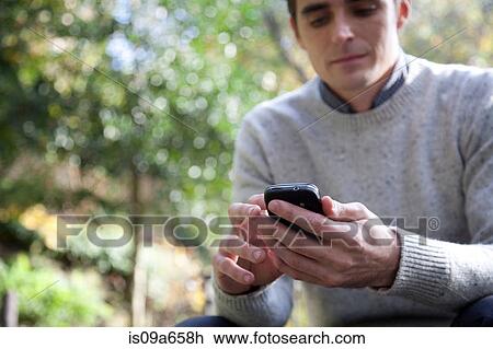 Man using cell phone outdoors View Large Photo Image Stock Image - Man using cell phone outdoors. Fotosearch