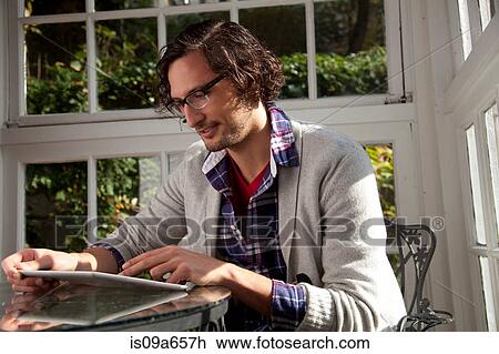 Stock Image - Man using tablet computer at table. Fotosearch