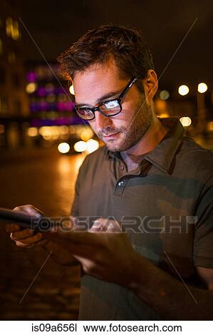 Stock Image - Man using tablet computer on city street. Fotosearch