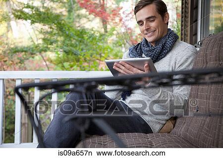Picture - Man using tablet computer on porch. Fotosearch