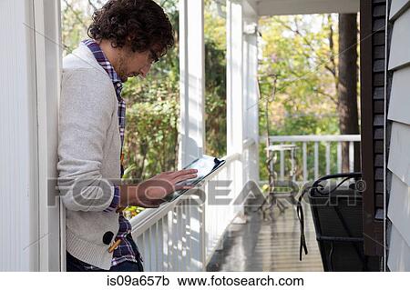 Man using tablet computer on porch View Large Photo Image Stock Image - Man using tablet computer on porch. Fotosearch