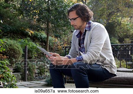 Stock Image - Man using tablet computer outdoors. Fotosearch