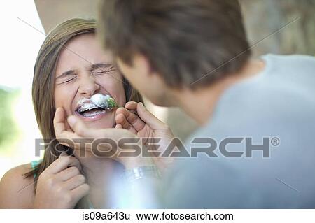 Stock Photograph - Man wiping coffee foam on girlfriend. Fotosearch