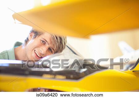 Stock Image - Man working on model airplane. Fotosearch