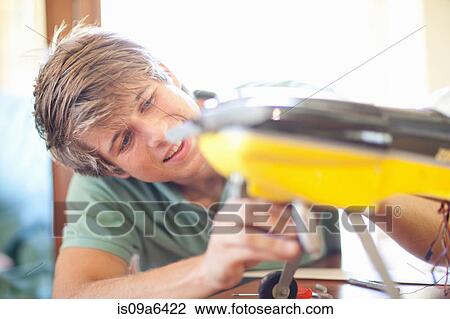 Stock Image - Man working on model airplane. Fotosearch