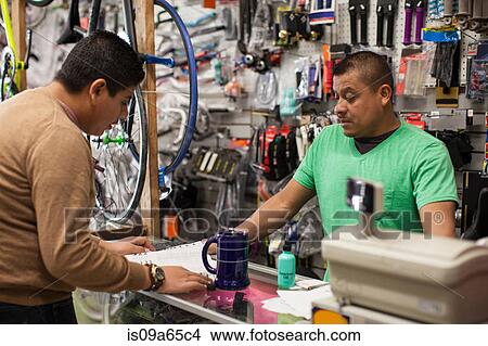 Picture - Mechanic and customer in bicycle shop. Fotosearch