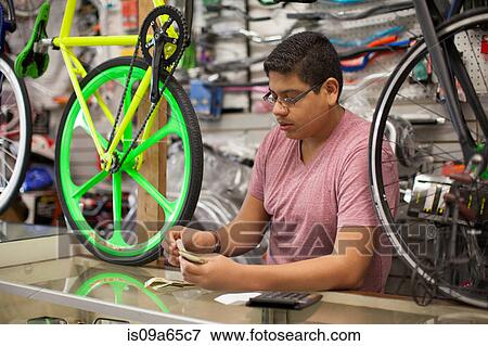 Stock Photo - Mechanic counting till in bicycle shop. Fotosearch
