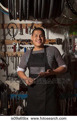 Stock Photo - Mechanic smiling in bicycle shop. Fotosearch