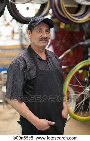 Mechanic standing in bicycle shop View Large Photo Image Stock Photo - Mechanic standing in bicycle shop. Fotosearch