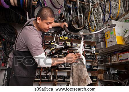 Stock Image - Mechanic working in bicycle shop. Fotosearch