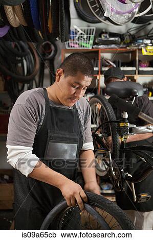 Stock Image - Mechanic working in bicycle shop. Fotosearch