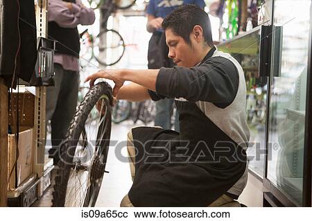 Stock Image - Mechanic working in bicycle shop. Fotosearch