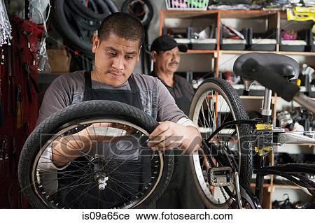 Stock Image - Mechanic working in bicycle shop. Fotosearch