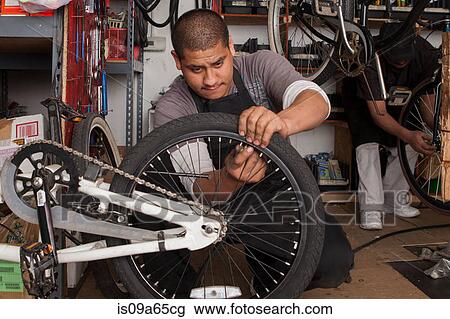 Stock Image - Mechanic working in bicycle shop. Fotosearch
