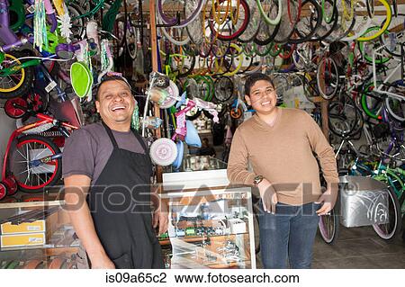 Stock Image - Mechanics smiling in bicycle shop. Fotosearch