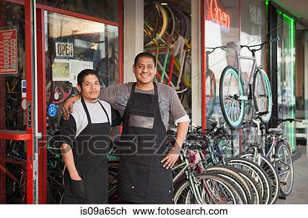 Stock Image - Mechanics smiling outside bicycle shop. Fotosearch