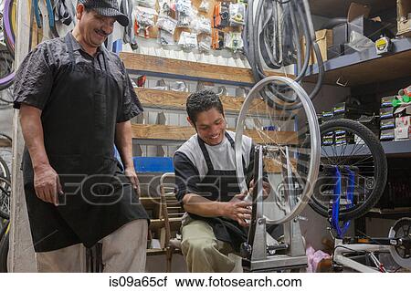 Stock Image - Mechanics working in bicycle shop. Fotosearch