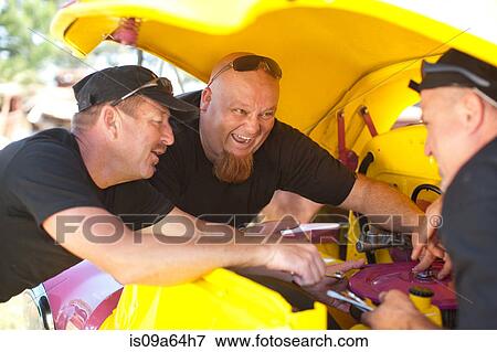 Stock Photo - Mechanics working on colorful car. Fotosearch