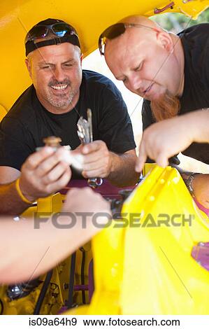 Stock Photo - Mechanics working on colorful car. Fotosearch