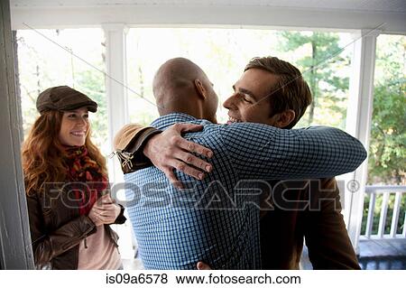 Stock Photo - Men hugging at front door. Fotosearch