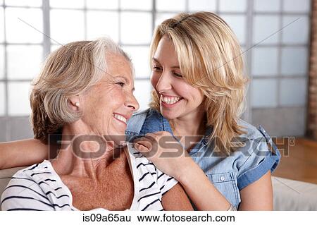 Stock Photograph - Mother and daughter relaxing on sofa. Fotosearch