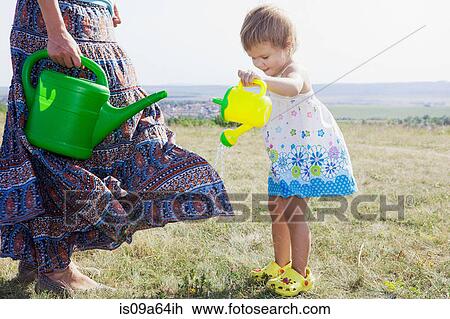 Stock Image - Mother and daughter watering plants. Fotosearch