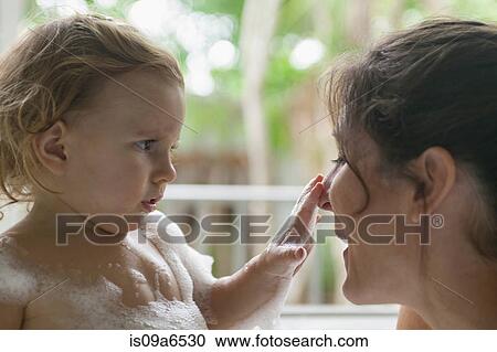 Stock Image - Mother and toddler in bubble bath. Fotosearch