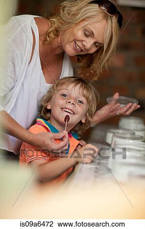 Stock Image - Mother giving son olive to taste. Fotosearch