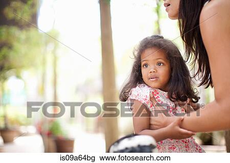 Stock Image - Mother picking up daughter outdoors. Fotosearch