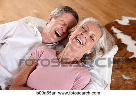 Stock Photography - Older couple laughing on sofa. Fotosearch