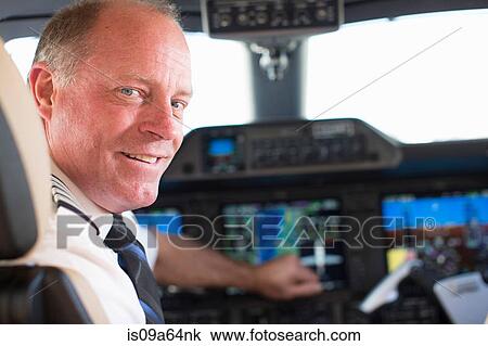 Stock Image - Pilot smiling in airplane cockpit. Fotosearch