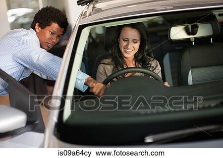 Stock Photo - Salesman showing woman new car. Fotosearch