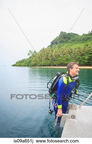 Stock Image - Scuba diver climbing into water. Fotosearch