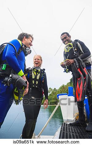 Stock Image - Scuba divers laughing on boat. Fotosearch