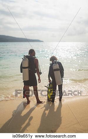 Stock Photo - Scuba divers walking on tropical beach. Fotosearch