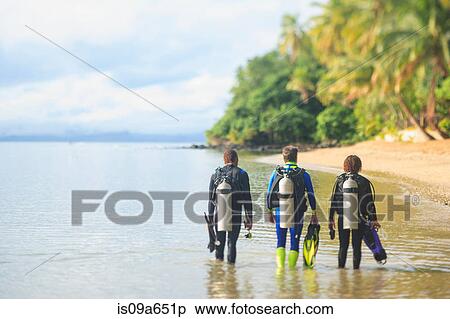 Stock Photography - Scuba divers walking on tropical beach. Fotosearch