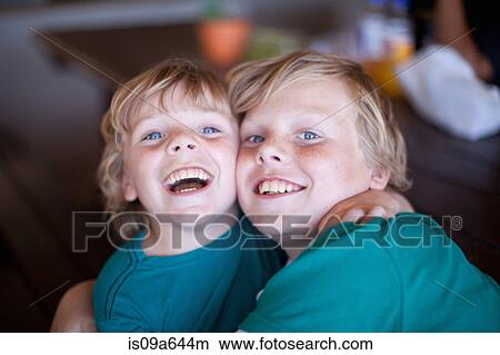 Picture - Smiling boys hugging in living room. Fotosearch