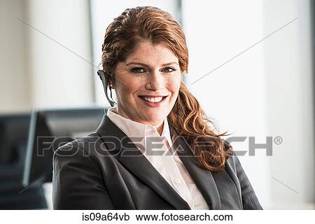 Stock Image - Smiling businesswoman wearing headset. Fotosearch