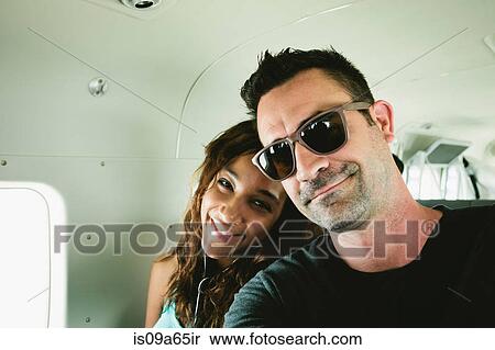 Stock Photography - Smiling couple sitting in airplane. Fotosearch