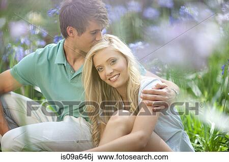 Stock Image - Smiling couple sitting in tall plants. Fotosearch