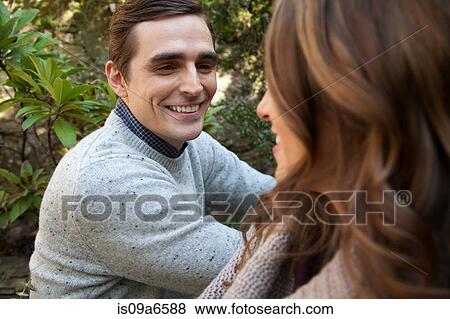 Stock Photo - Smiling couple sitting together outdoors. Fotosearch